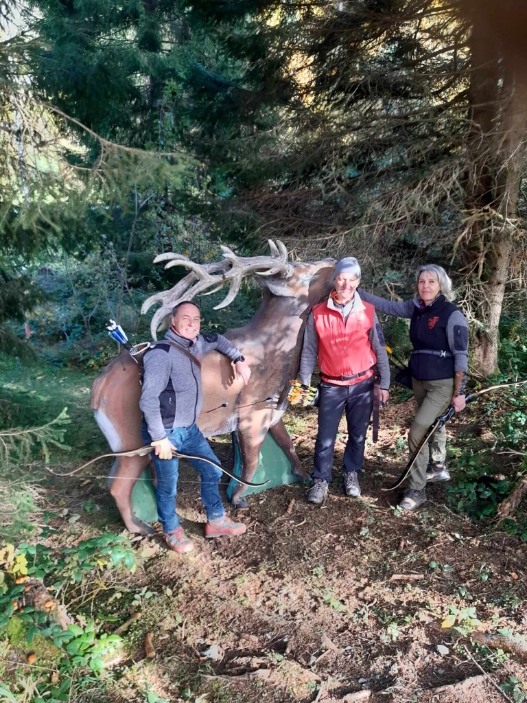 Drei Bogenschützen posieren vor einem Ziel in der Natur, bereit für das Training im Jagdbogenclub.