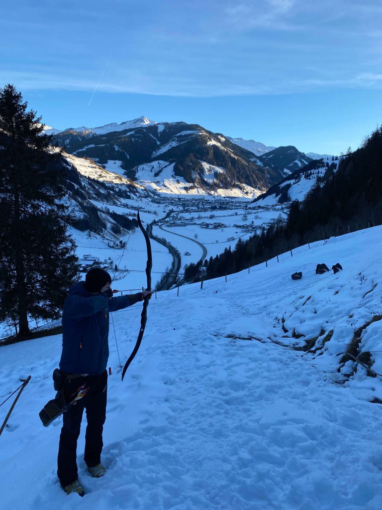 Bogenschütze zielt im schneebedeckten Gelände der Berge von Rauris.